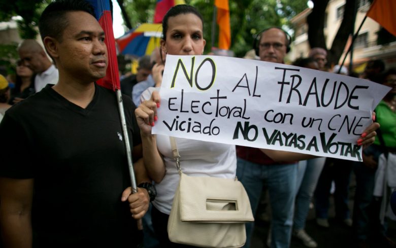 Mulher carrega um cartaz com a mensagem ‘Não à fraude eleitoral com um Conselho Eleitoral Nacional viciado. Não vote’ durante protesto contra as eleições presidenciais em Caracas, na Venezuela, na quarta-feira (16) (Foto: AP Photo/Ariana Cubillos)